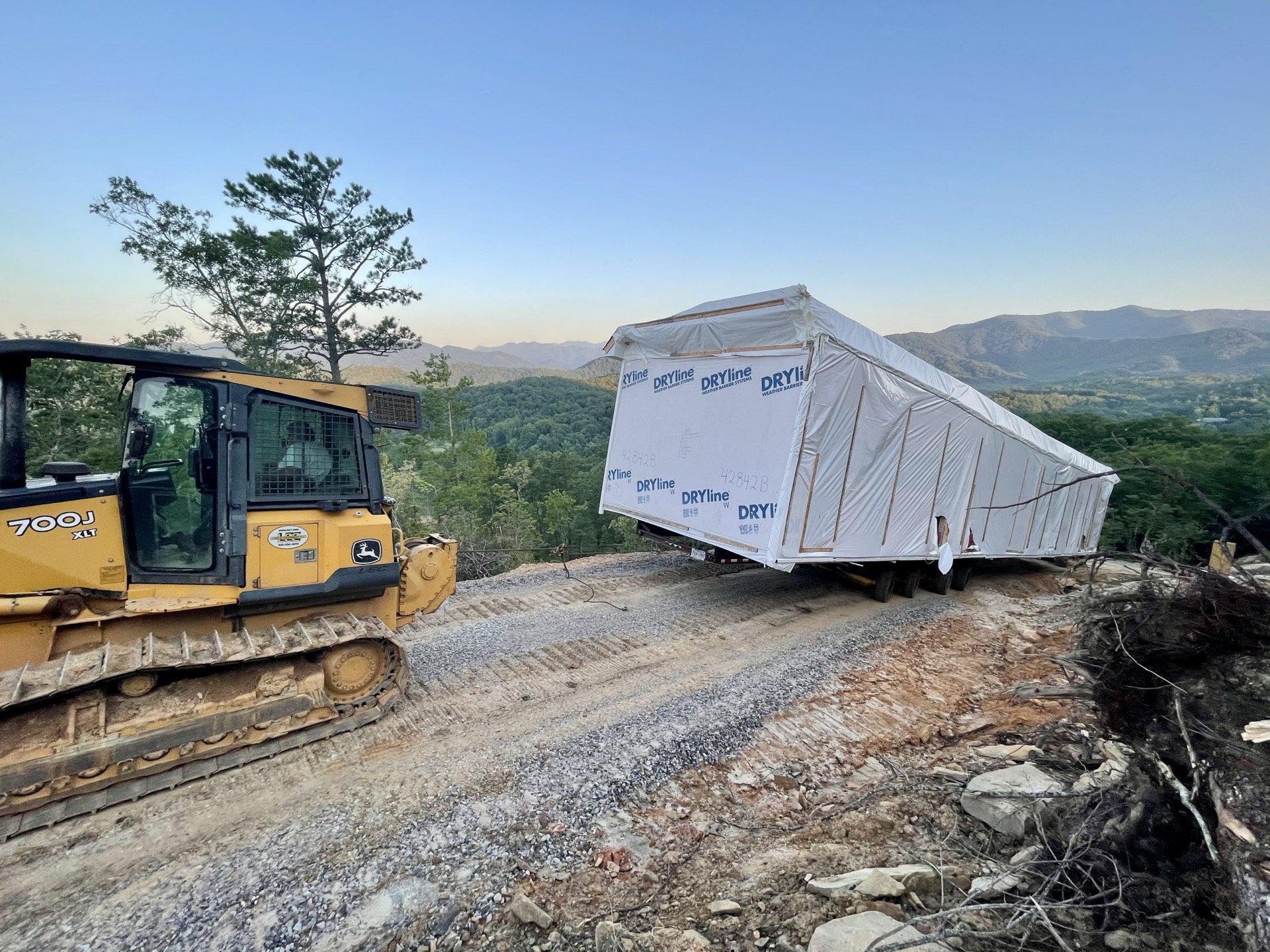 Mountain Movers maneuvering a home along a mountain road at sunset